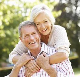 senior couple where the wife is hugging her husband from behind